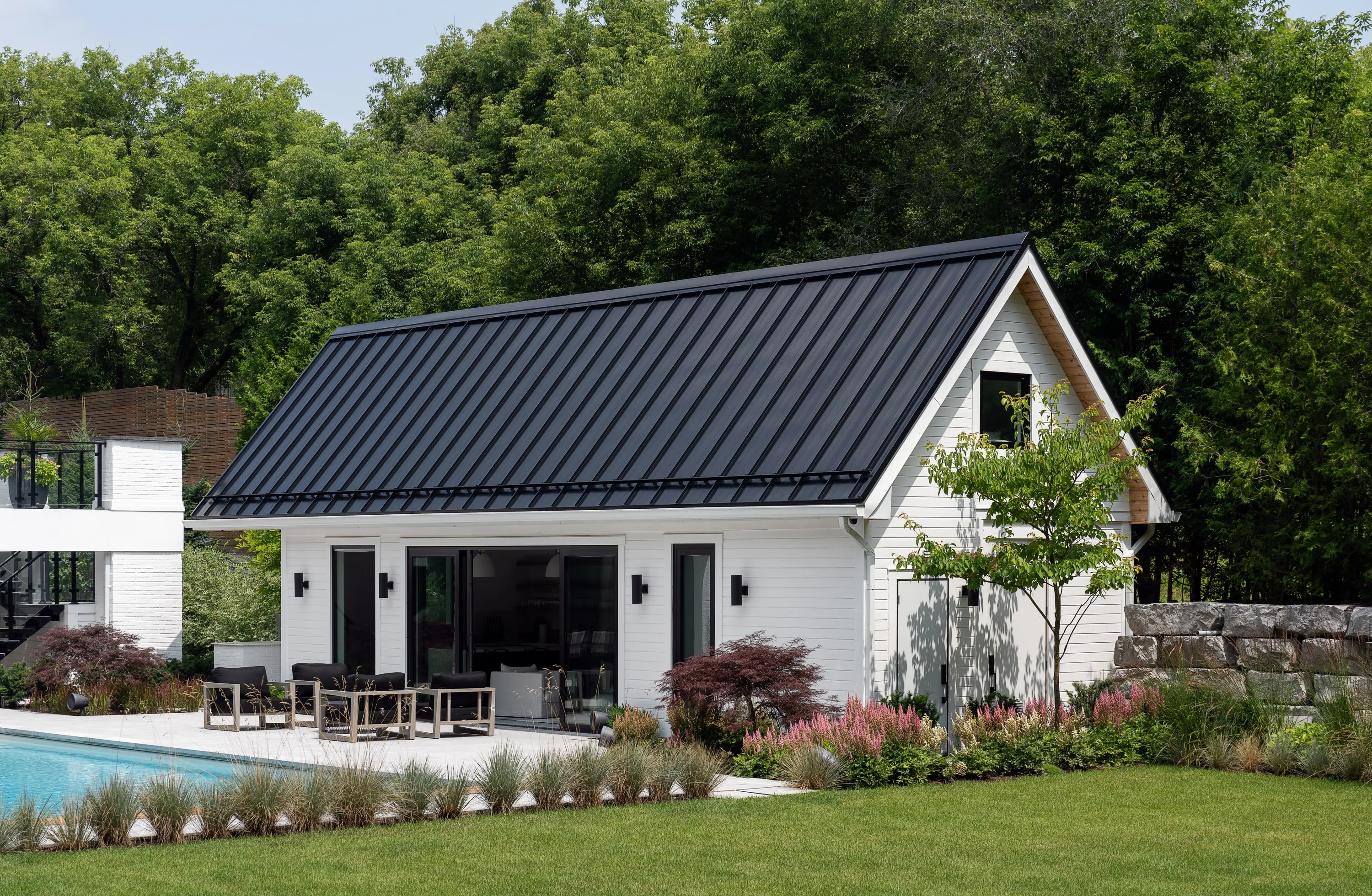 Pool house with a standing-seam roof beside the pool.