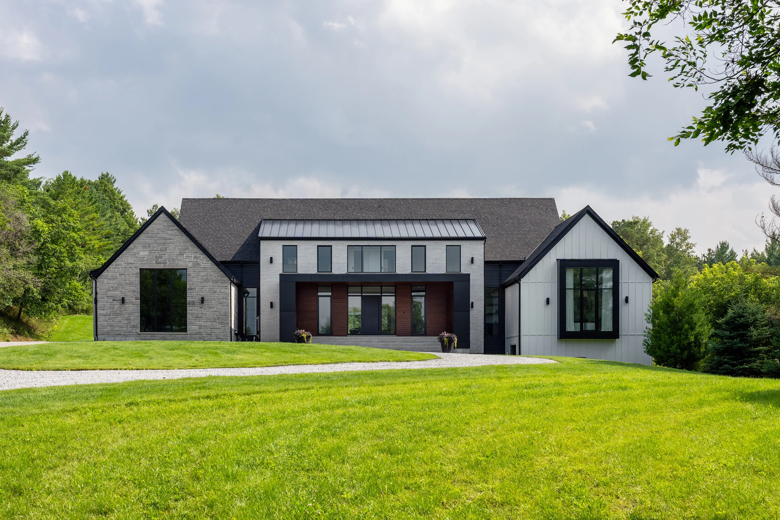 Front elevation of a brick and board residence with a recessed timber entry, seen across an open lawn.