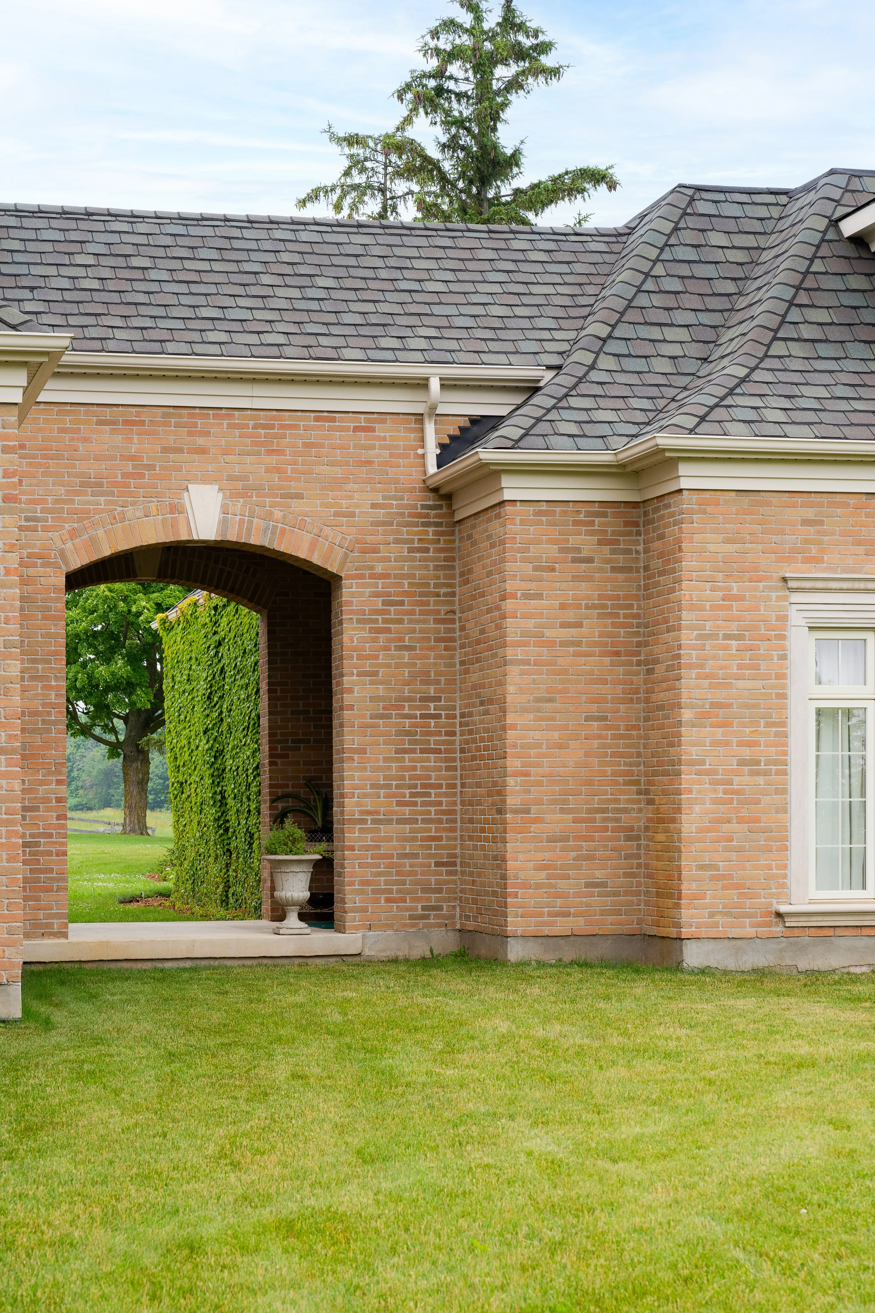 Arched brick passage with a clipped hedge.