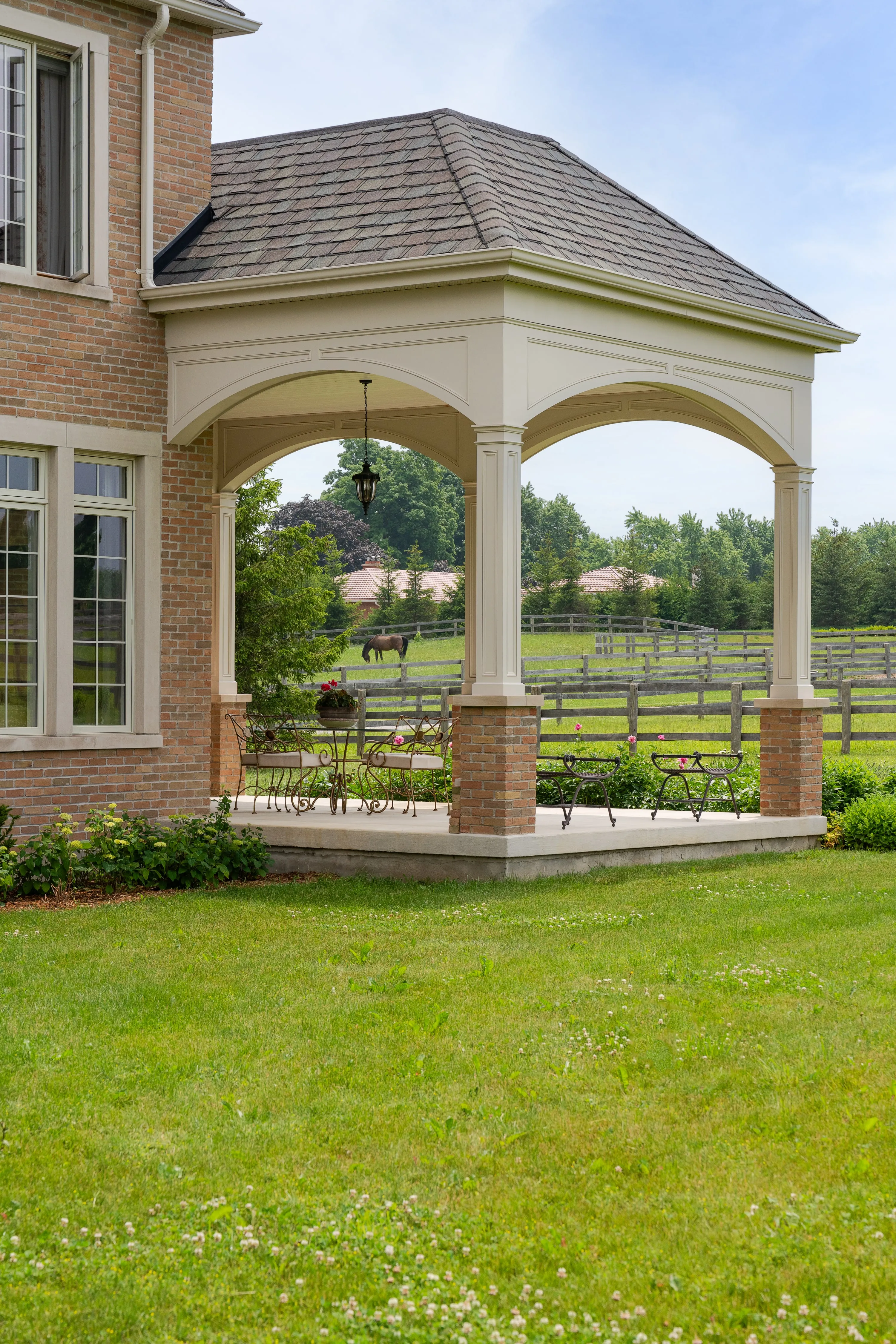 Covered breezeway with arched openings and a view to the fields.