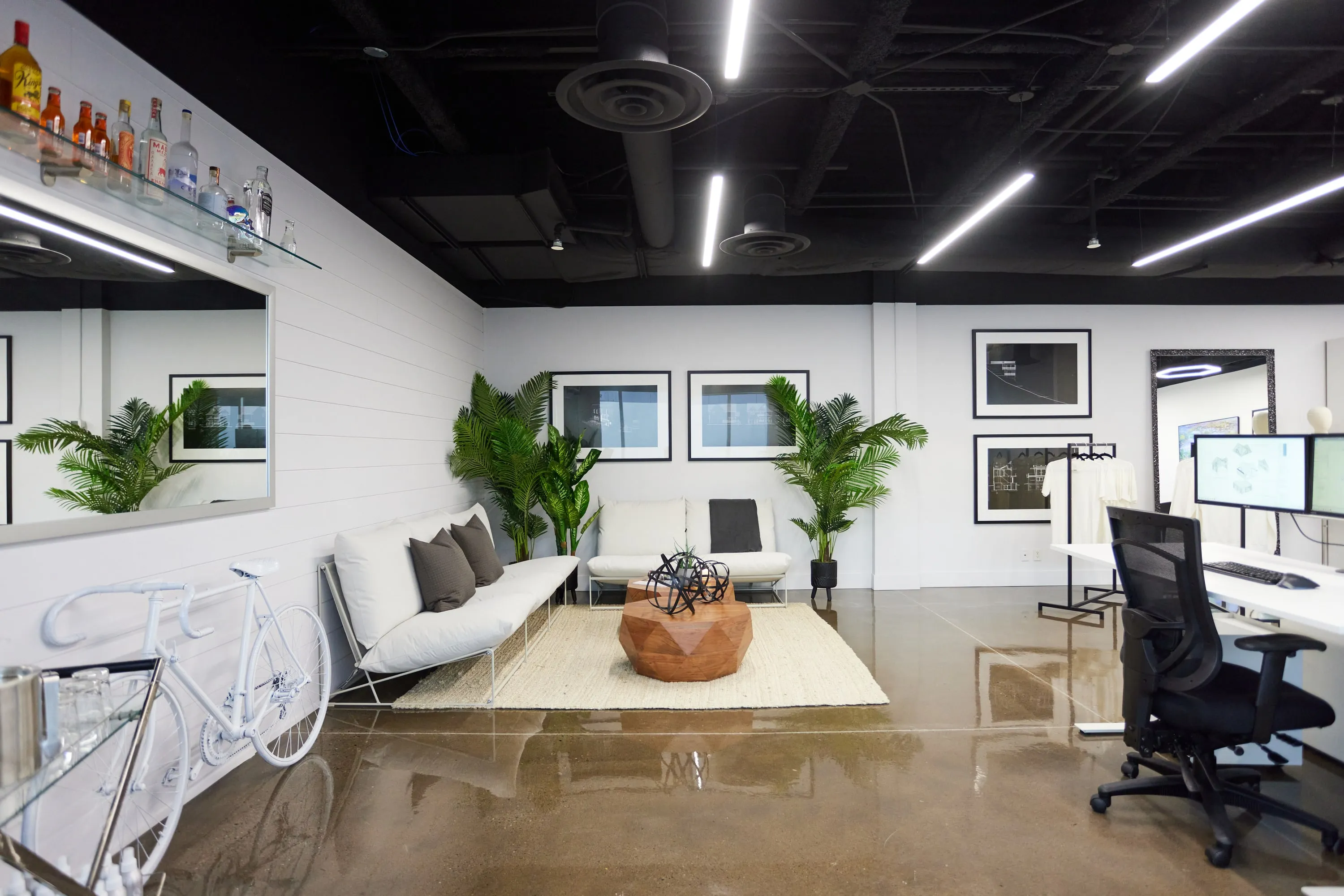 The Stamp & Hammer studio: a white lounge, desks and framed drawings under a black ceiling.