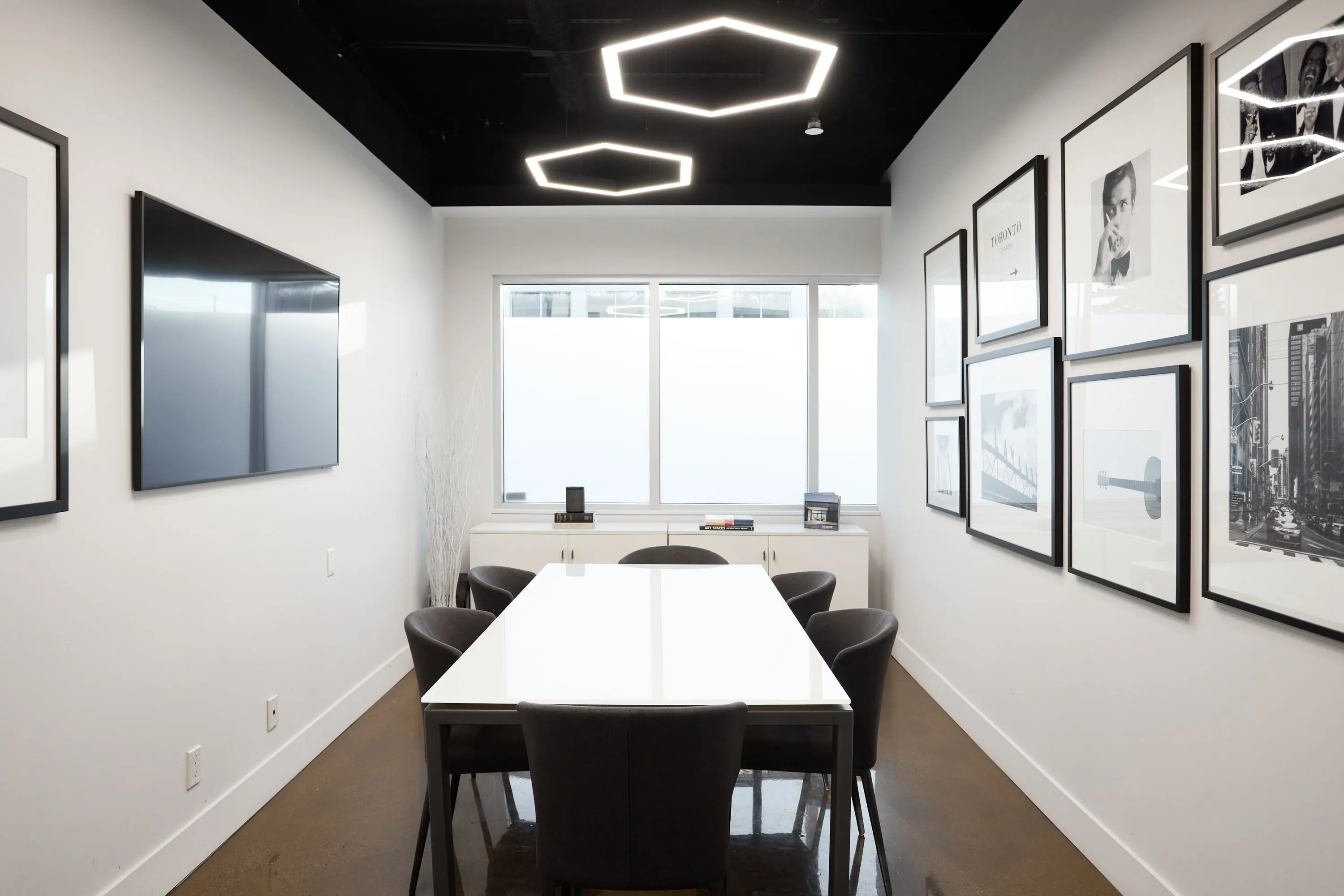 The meeting room: a white table under a hexagonal light, framed drawings along one wall.